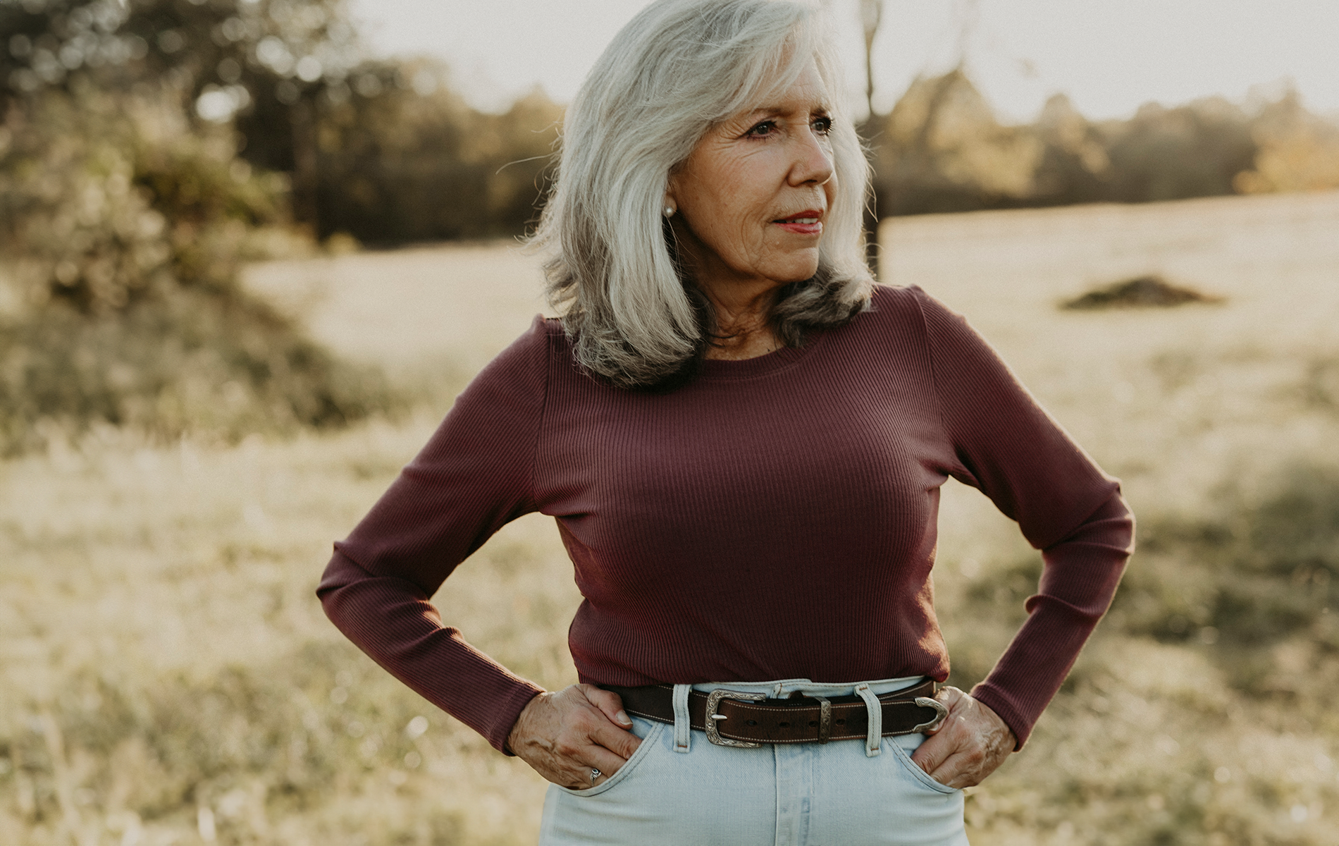 Woman modeling Willow Western belt with grassy fields in back