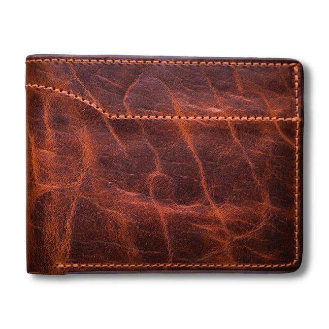 The Powell Bison Bifold with ID Window by Hanks Belts is a brown wallet made from bison leather, featuring visible stitching and a slightly worn texture. It combines vintage charm with durability and ample storage for style and function.