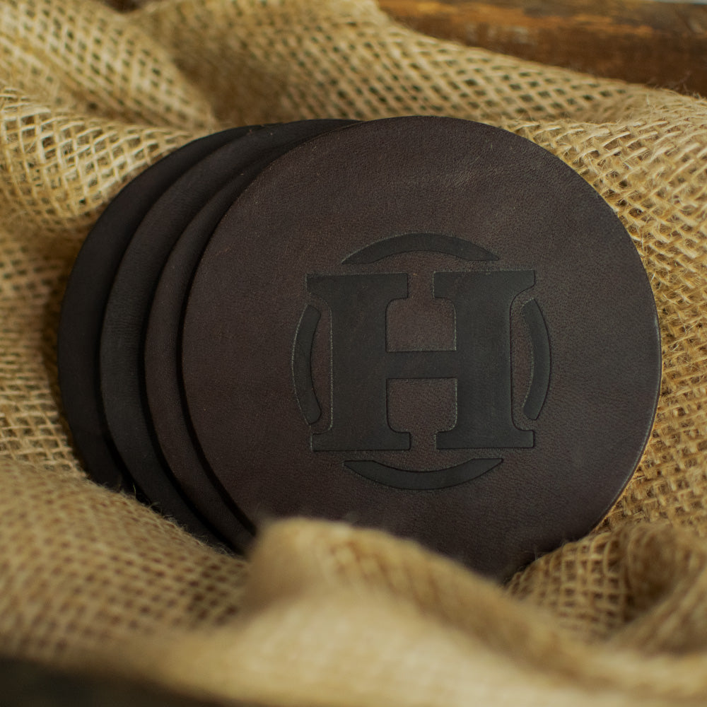 Set of 4 round leather coasters laying on burlap in rich brown