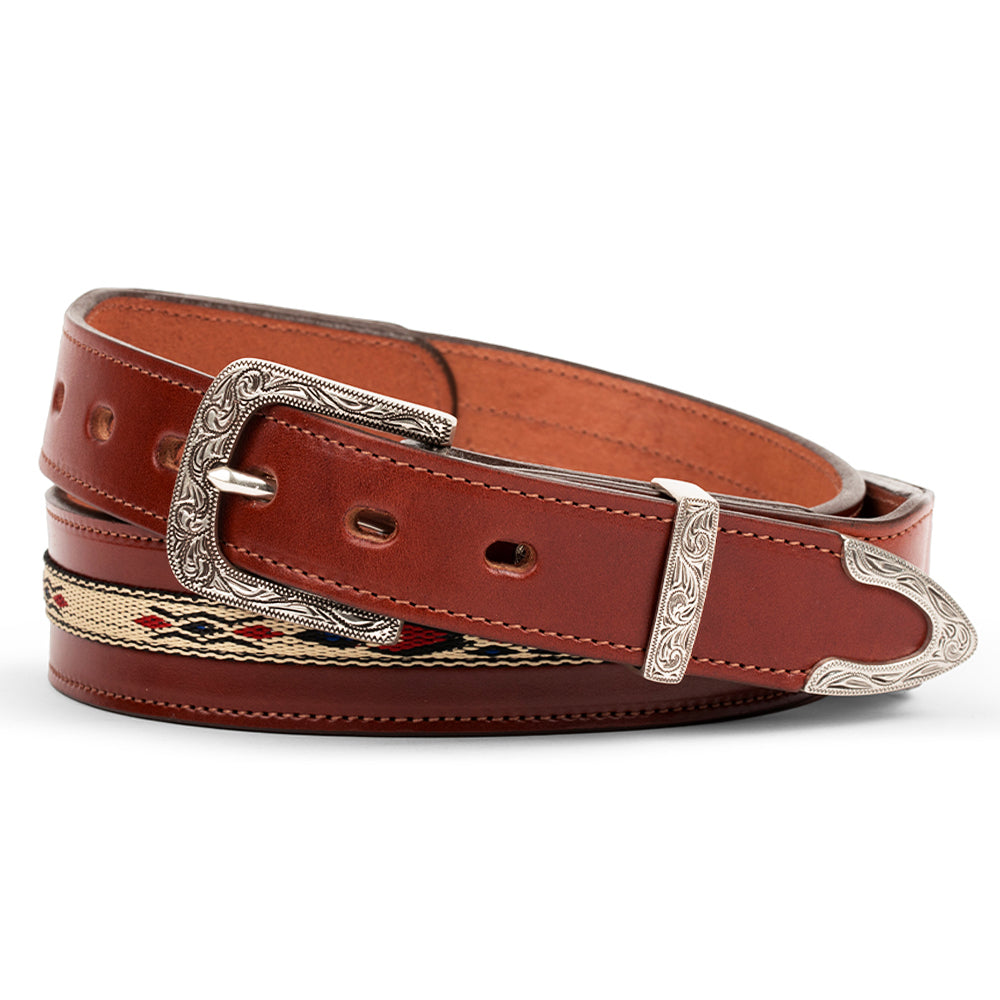 The Seneca - 1.5&quot; by Hanks Belts is a brown leather belt featuring an intricate silver buckle, decorative engraved patterns, and a woven section with red, black, and beige accents for Western flair. Made from Premium English Bridle Vegetable-Tanned Leather for lasting quality.