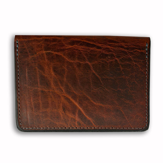 The Diablo Slimline Card Holder by Hanks Belts is a brown Bison Leather wallet featuring a smooth texture and visible stitching along the edges. This rectangular slimline card case has a slightly worn appearance that gives it a vintage look. Crafted in the USA, it is showcased against a plain white background.