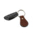 A black car key fob with several buttons is attached to a metal ring along with a Hanks Belts Bell-Shaped Leather Keychain, crafted from full grain oak leather. The keychain features white stitching and an embossed circular logo on the leather. The background is plain white.