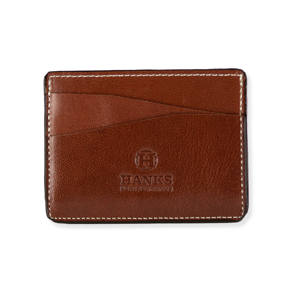 The Monroe Goatskin Card Holder by Hanks Belts is a brown leather wallet with a smooth texture, embossed with the logo and text &quot;HANKS LEATHER GOODS&quot; on the front. This minimalist wallet features two diagonal card slots on one side, a slim profile, and white stitching along the edges.