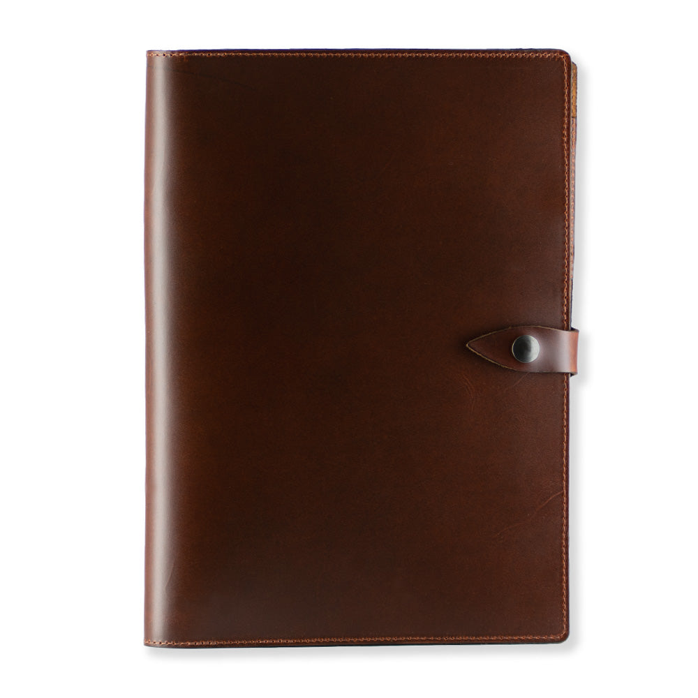 The Luxury Folio by Hanks Belts, a closed brown full-grain leather portfolio with a buttoned strap closure, is shown against a plain white background. Made in the USA, this high-end folio boasts a smooth surface and visible stitching along the edges.