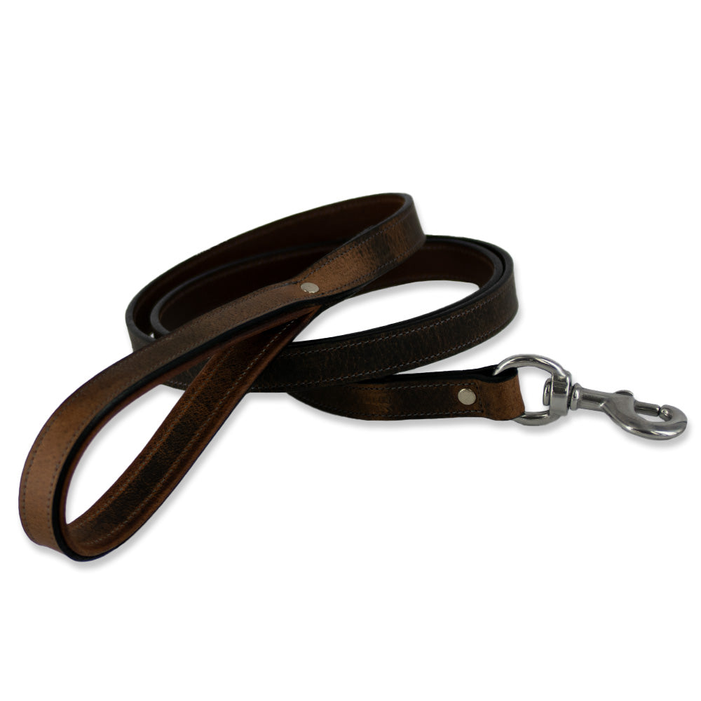 A Kodak Leash from Hanks Belts lies coiled, crafted from Premium Bison Leather with stainless steel hardware. The leash showcases a loop handle at one end and a metal clasp at the other for attaching to a collar, along with natural leather texture and detailed stitching along the edges.