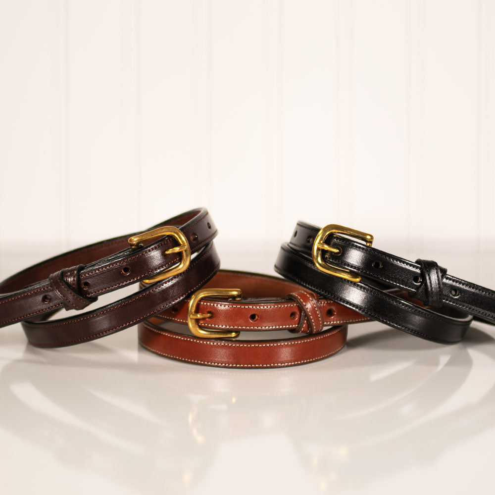 Three &quot;Dixie Belt - .75&quot;&quot; women&#39;s belts from Hanks Belts, crafted from Premium English Bridle leather and featuring rounded brass buckles, are arranged on a white surface. One belt is dark brown, one is light brown, and the other is black. The belts are coiled neatly with their buckles prominently displayed in the foreground.