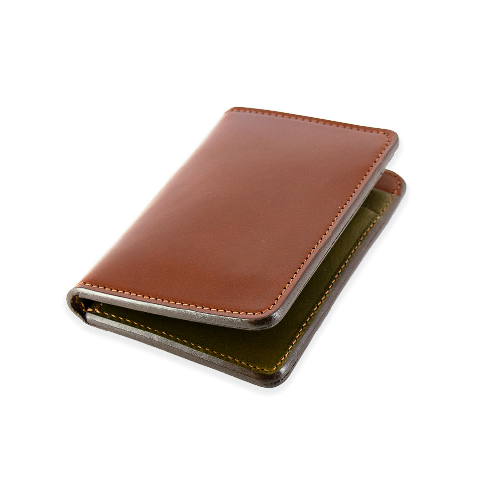 The Superior Front Pocket Bifold by Hanks Belts showcases a minimalist USA-made design. Crafted from premium English bridle leather, the partially open wallet reveals a green interior and visible stitching, all set against a plain white background.