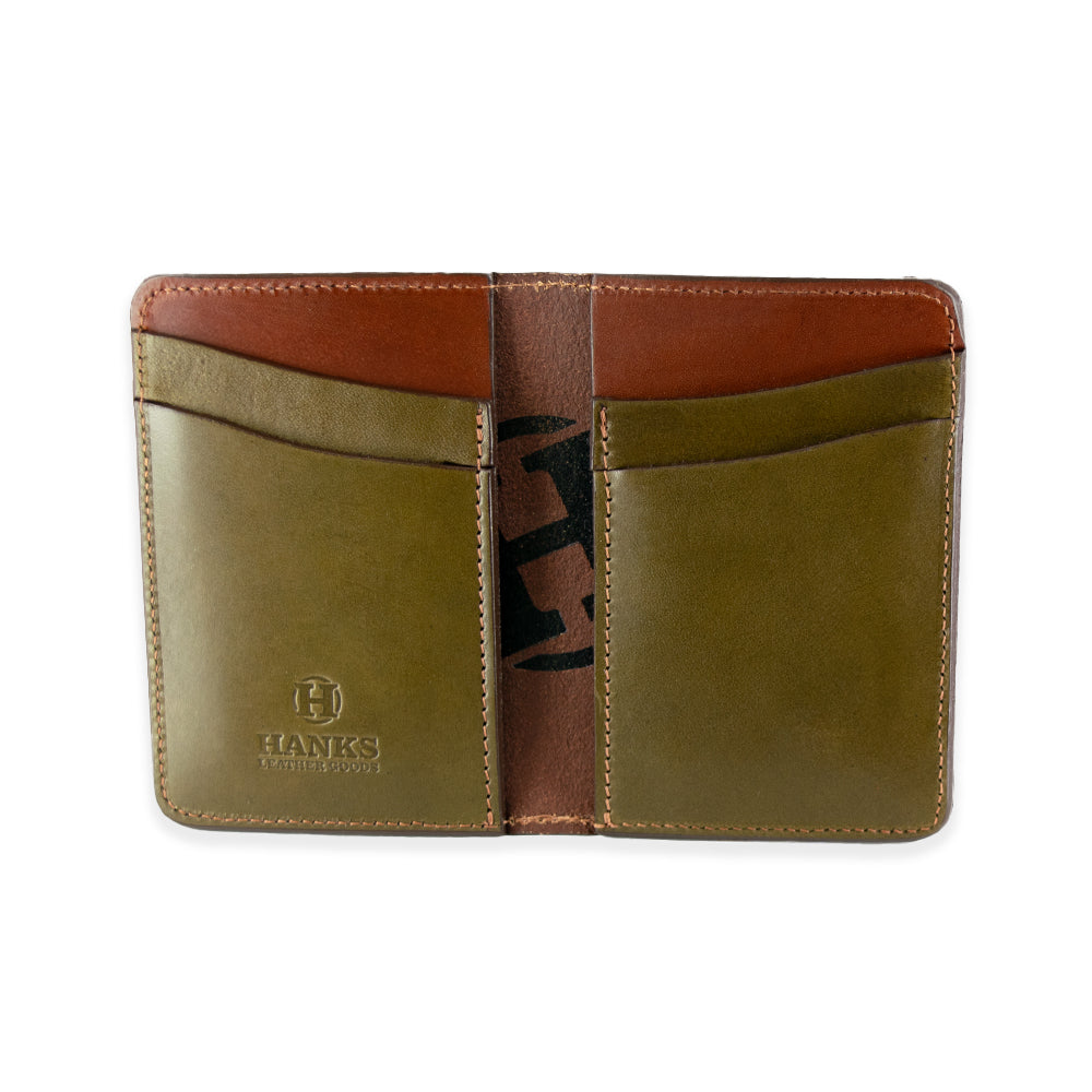 The Superior Front Pocket Bifold by Hanks Belts features an open design with two tan card slots on each side, visible stitching, and is crafted from premium English bridle leather. An embossed logo adorns the bottom left corner while a brown interior with partially visible black design highlights its handcrafted quality.