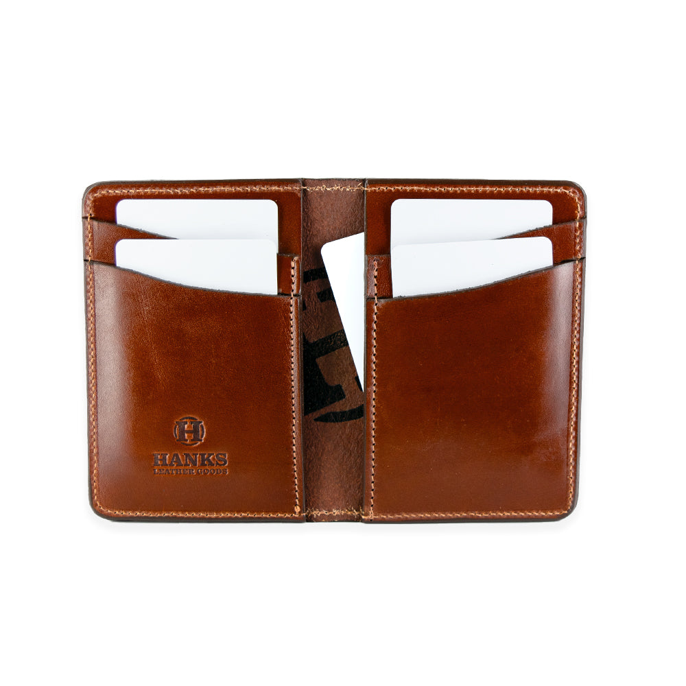 The Superior Front Pocket Bifold from Hanks Belts is an open brown handcrafted wallet with two sections, each holding three white cards. Made from USA-tanned leather, it features &quot;HANKS&quot; and a logo embossed on the bottom left corner.