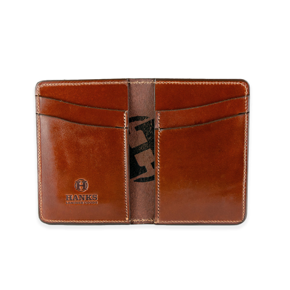 The Superior Front Pocket Bifold by Hanks Belts is an open brown leather wallet featuring four card slots made from premium harness leather. It has the &quot;Hanks Belts&quot; logo embossed on the bottom left, with visible stitching around the edges and card slots highlighting its handcrafted appeal.