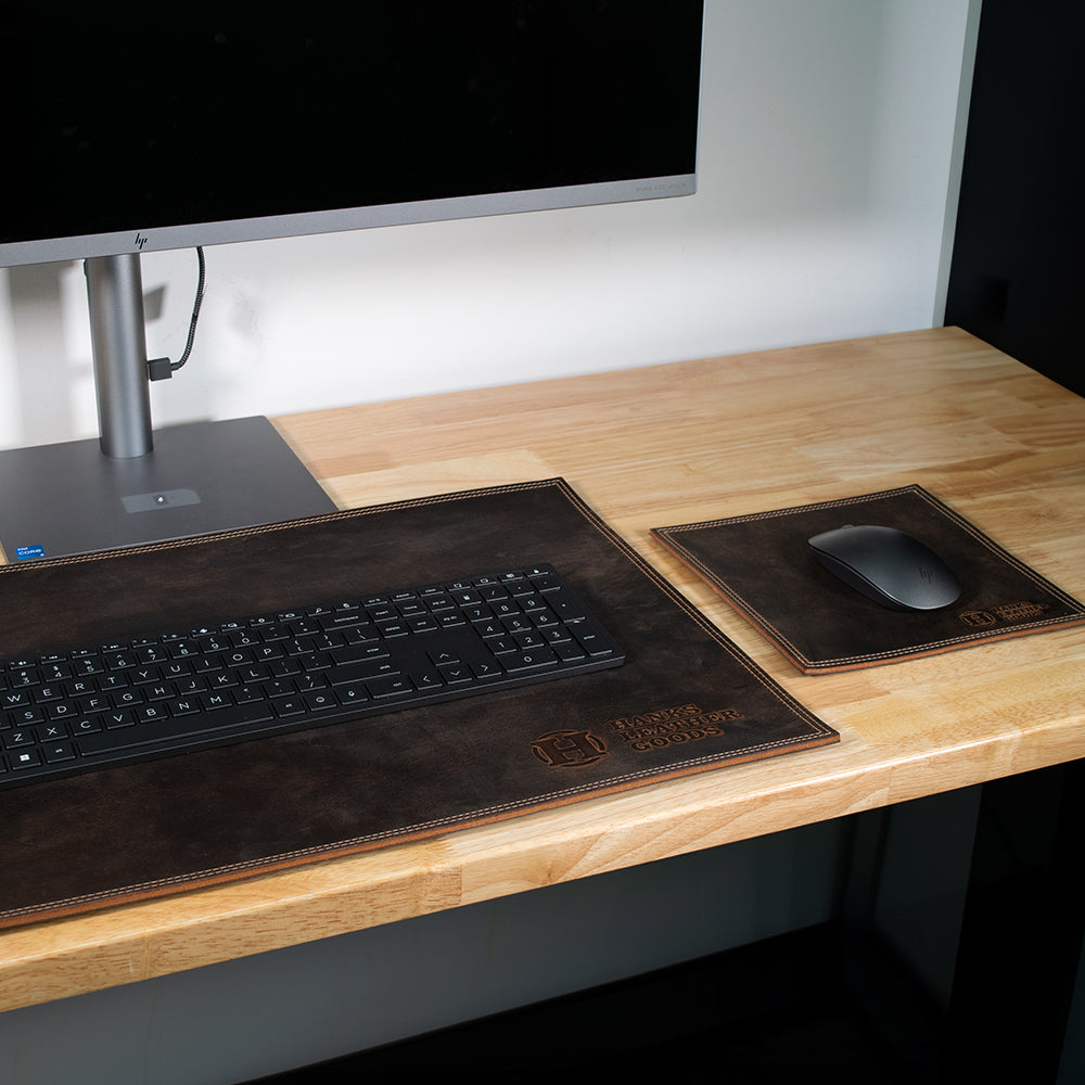 A brown Desk & Mouse Pad Set paired with a matching coaster, crafted from North American Bison Leather and embossed with the "Hanks Belts" logo at the bottom corner. Handmade in the USA, this set exudes a rustic, worn-in charm.