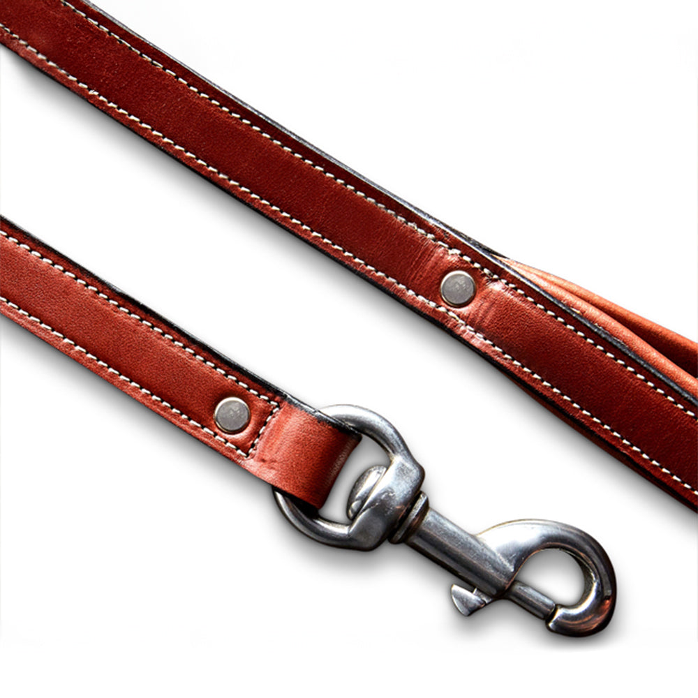 Close-up of the Rover Leash by Hanks Belts, made from English Bridle leather with white stitching and metal rivets. A silver clip gleams at the end, and the brown leather leash lies diagonally against a white background.