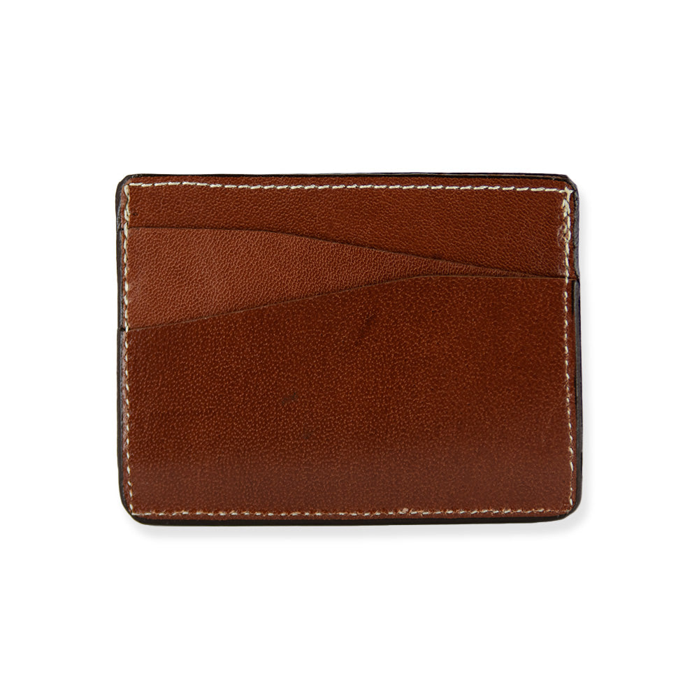 The Monroe Goatskin Card Holder by Hanks features a minimalist design in brown goatskin leather. It boasts visible stitching details along the edges and a slim profile with several card slots on the front. The product is photographed against a plain white background.