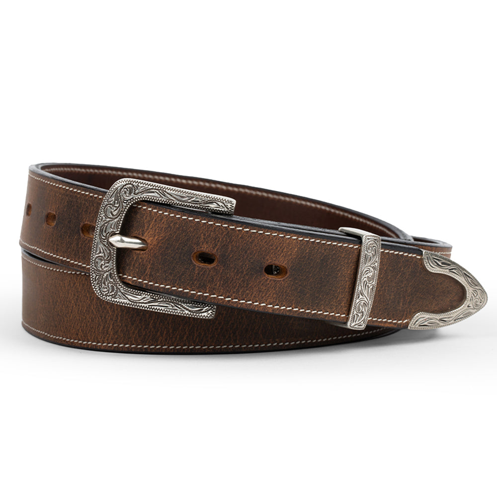 The Dakota Belt - 1.25&quot; by Hanks Belts is a brown leather accessory made from North American bison, featuring an ornate silver floral buckle and tip with intricate designs. It offers a smooth texture and adjustable holes for a perfect fit, complemented by silver elements for a Western look.