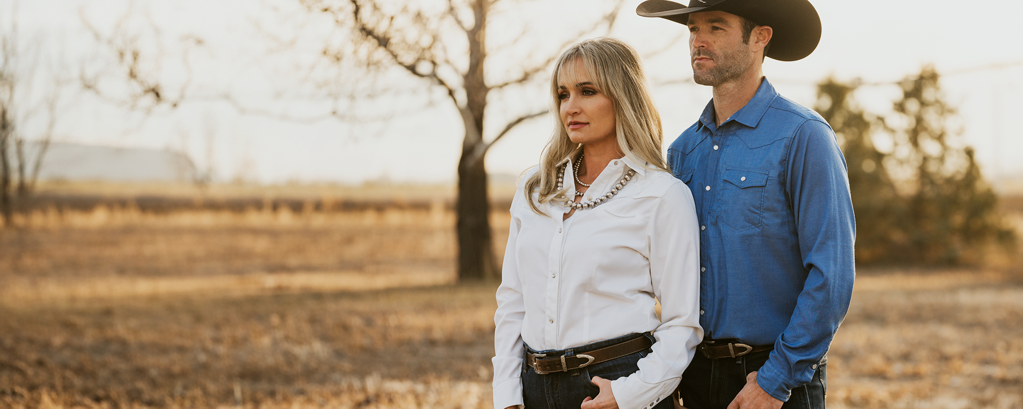 Man and woman standing together wearing hanks belts in a field