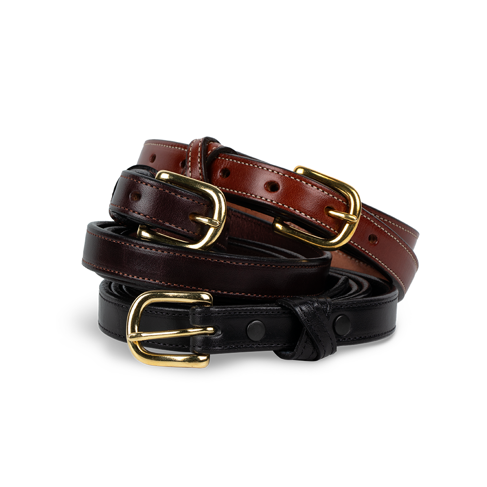 The Dixie Belt by Hanks Belts is a versatile accessory comprising three premium leather women&#39;s belts, each with polished gold buckles. The set includes dark brown, reddish-brown, and black belts, all with smooth textures and multiple perforations.