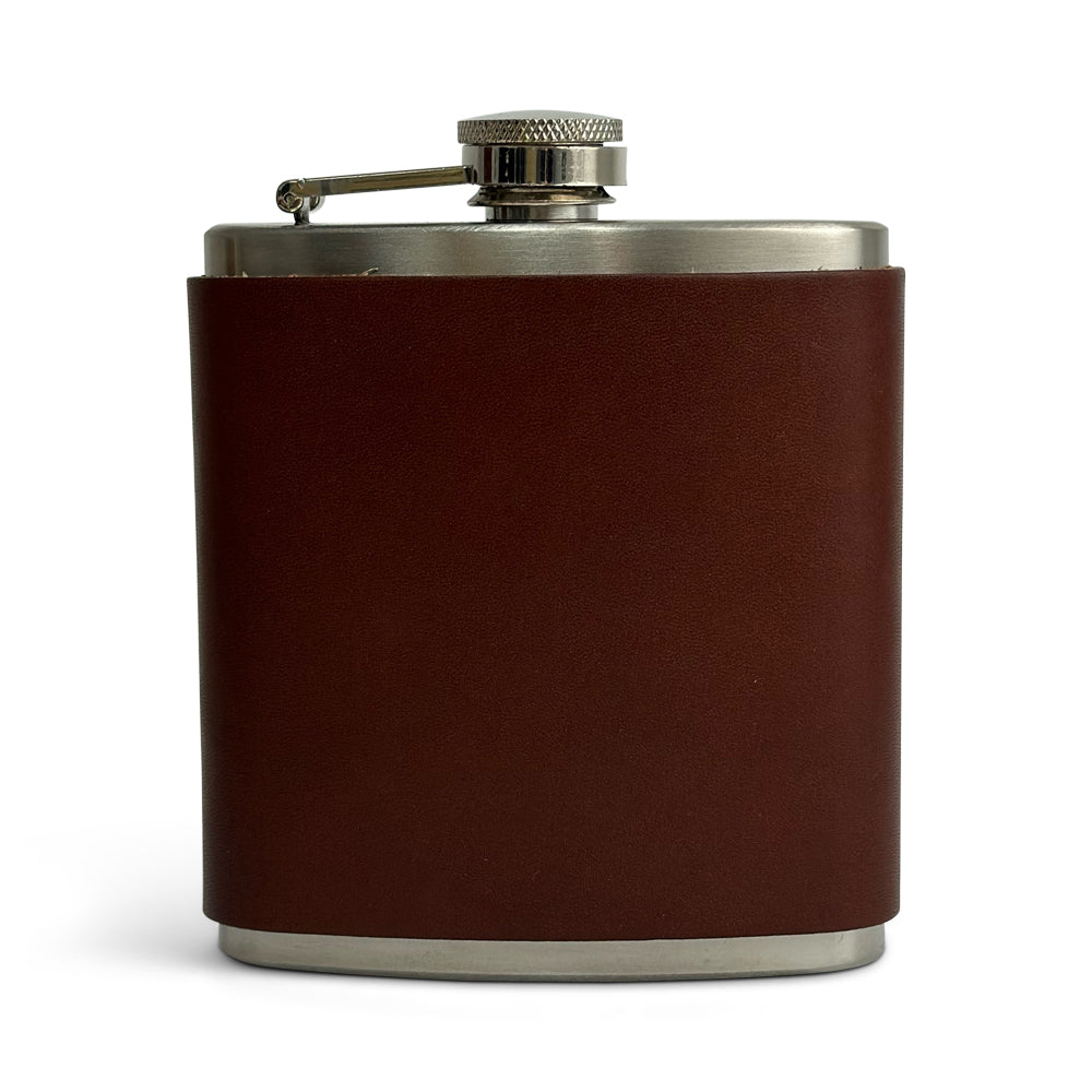 The Hanks Belts Leather Covered Flask, crafted from stainless steel and wrapped in oak-colored USA tanned leather with a screw-on cap that includes a hinged arm, is shown standing upright against a white background.