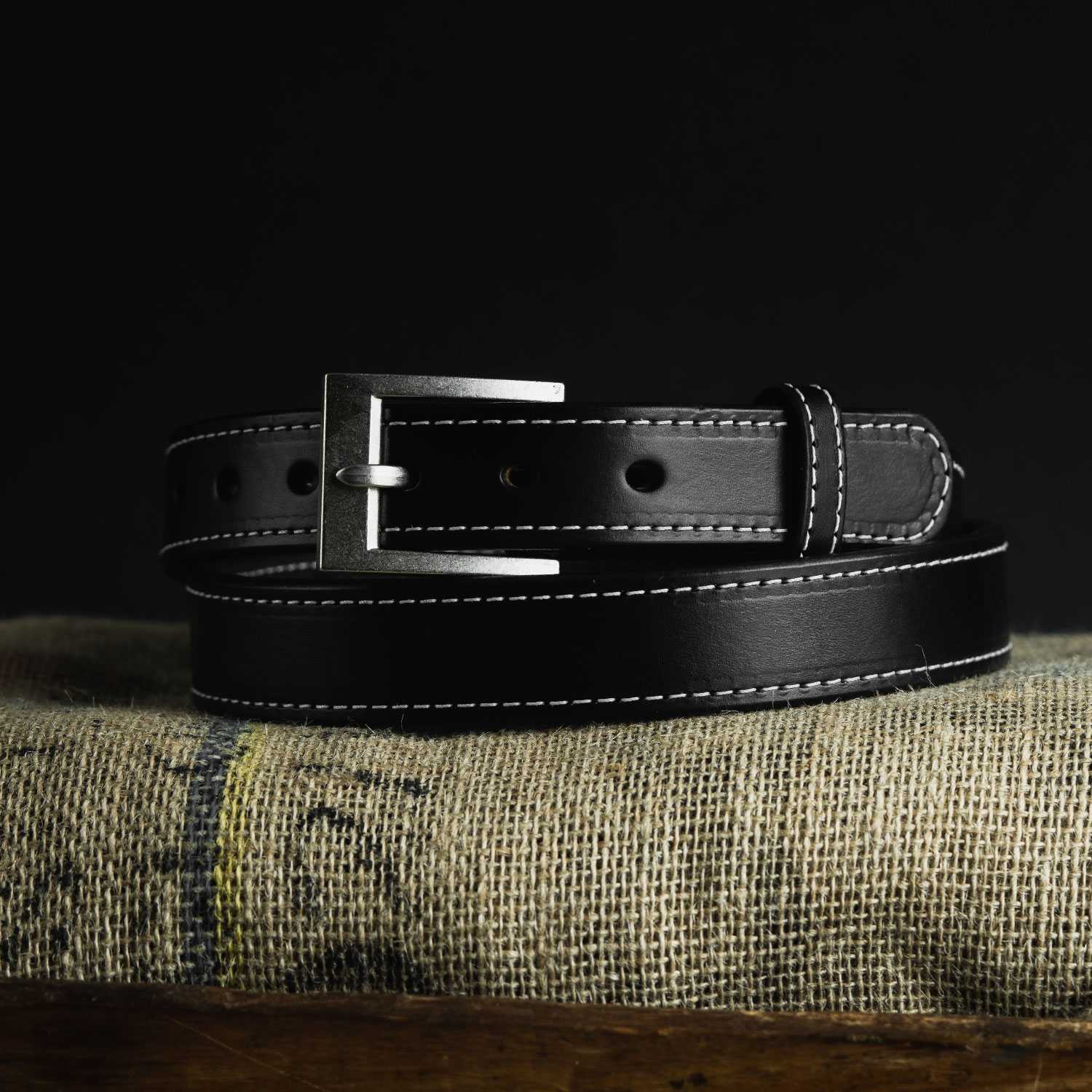 Presenting the Hanks Belts Bonnie Belt - 1.25", a black handcrafted coiled leather accessory with visible white stitching and a silver rectangular buckle. Made from full-grain leather, it includes multiple adjustment holes for a customizable fit and eye-catching style.